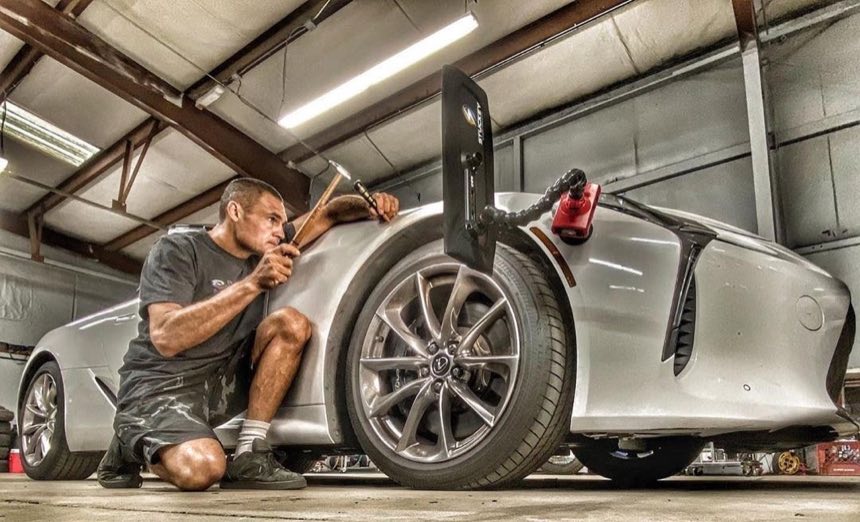 1-800-DENT-DOC technician performing paintless dent repair on a white sports car