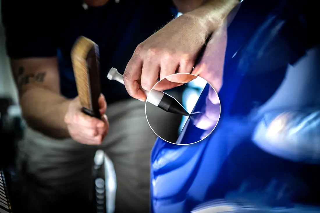 PDR technician tap-down work on a blue panel, knockdown and hammer in hand