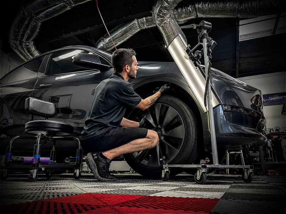 1-800-DENT-DOC technician performing paintless dent repair on a black Tesla