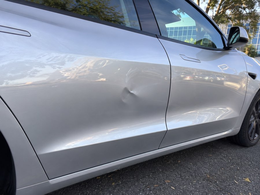 Dent on a silver Tesla door panel before paintless dent repair