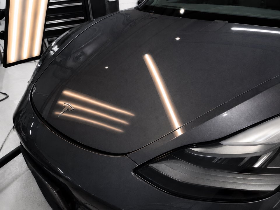 Tesla hood after paintless dent repair — reflection lines straight, dent gone